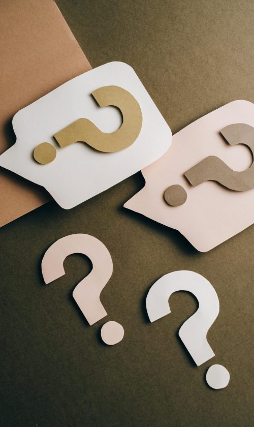Artistic paper cutouts of question marks creating a conceptual design on a brown surface.