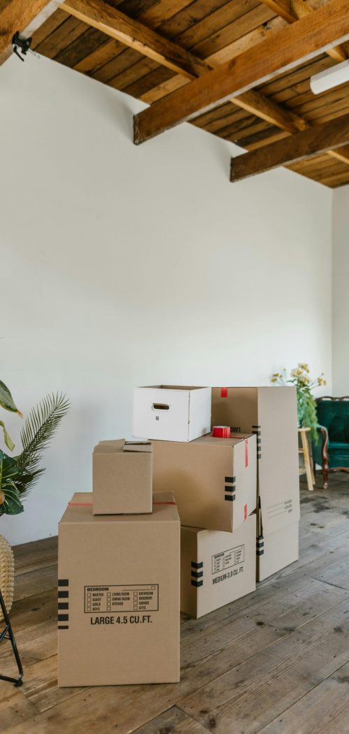 A spacious room with wooden floors and stacked cardboard boxes, ideal for moving concepts.